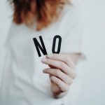 Image of a woman holding up two letters that spell the word no