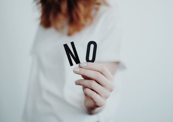 Image of a woman holding up two letters that spell the word no