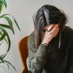 Picture of a woman sitting with her head in her hands while working at home