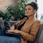 Image of a woman sitting on a couch working casually on her laptop